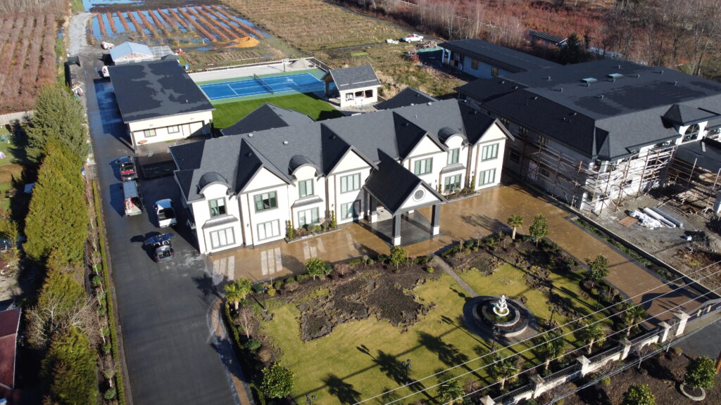 Aerial view of a large, white building with a gray roof, located at 10577 Blundell Road, surrounded by a parking lot and landscaping, with construction ongoing nearby.