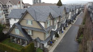 Aerial view of a townhome development in Alberta with rows of similar-looking gray and beige townhouses, featuring gabled roofs and small front yards.