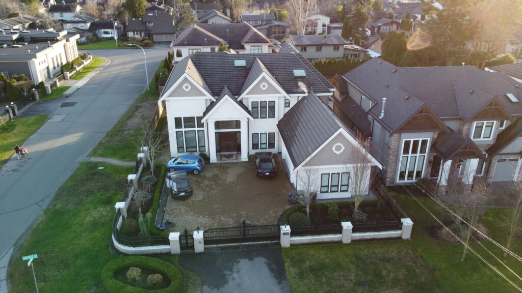 Aerial view of a residential neighborhood on Coldfall Road showing large houses with steep roofs, well-maintained lawns, and a driveway with cars.