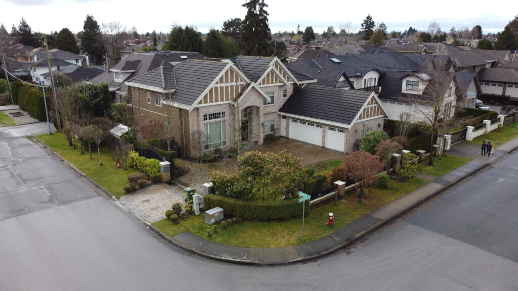 Aerial view of a large suburban house at 5789 Langtree Avenue with a neatly trimmed lawn and a driveway, surrounded by similar homes in a quiet neighborhood.