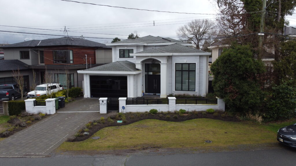 Aerial view of a modern two-story house on Forsyth Crescent with a white facade, black trim, and a landscaped front yard in a residential area.