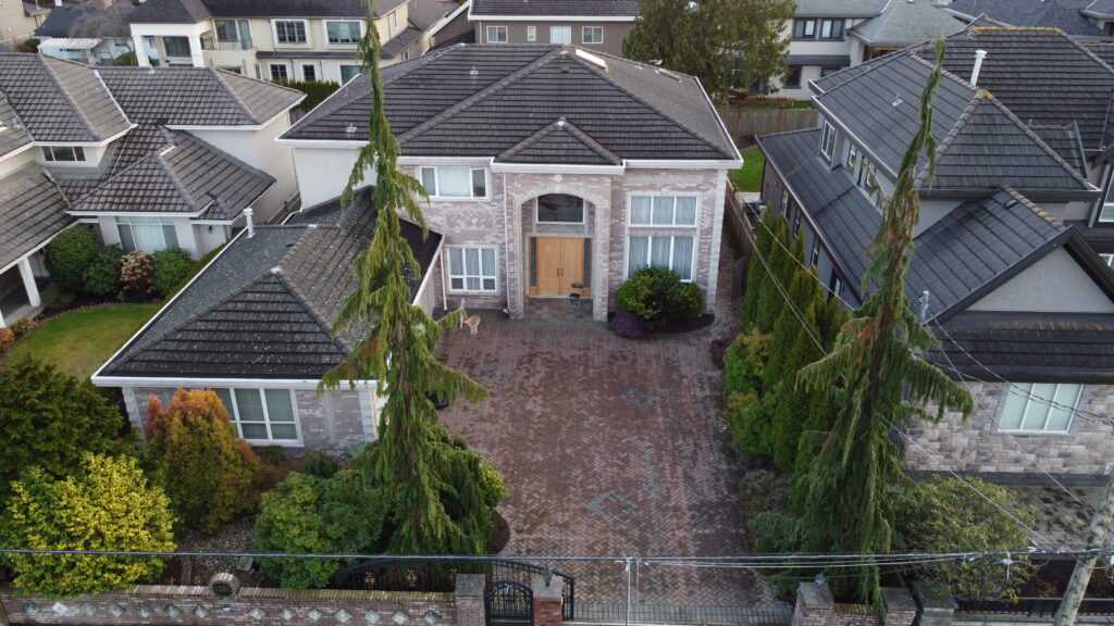 Aerial view of a large suburban home at 6380 Comstock Road with a brick driveway, surrounded by other houses and greenery.