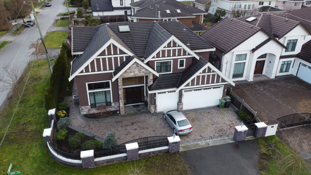 Aerial view of two large, suburban homes at 6380 Comstock Road with distinct gabled roofs and landscaped front yards, one with a parked car in the driveway.