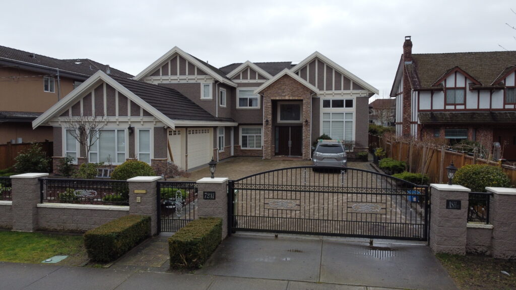 A modern two-story house on Ash Street with a gray facade and white trim, featuring a double garage and a gated driveway with a parked car.