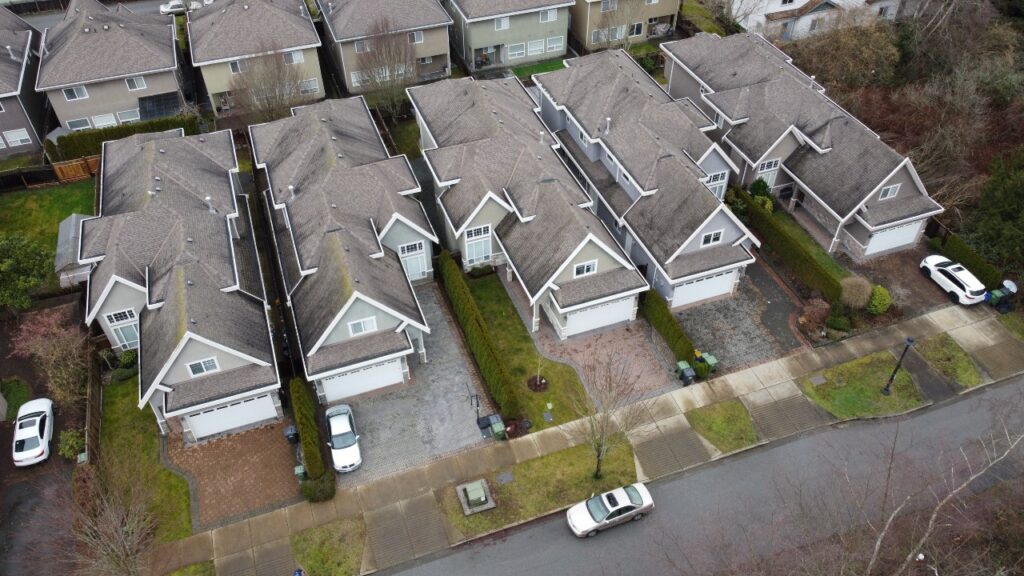 Aerial view of a suburban neighborhood in General Currie showing rows of similar two-story houses with gray roofs, driveways with parked cars, and green lawns.