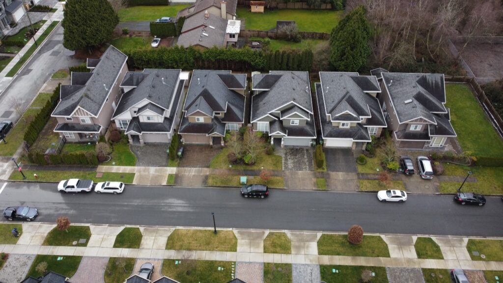 Aerial view of HOME DEVELOPMENT on Sills Ave 6, showing rows of similar two-story houses with driveways and parked cars, surrounded by green lawns.